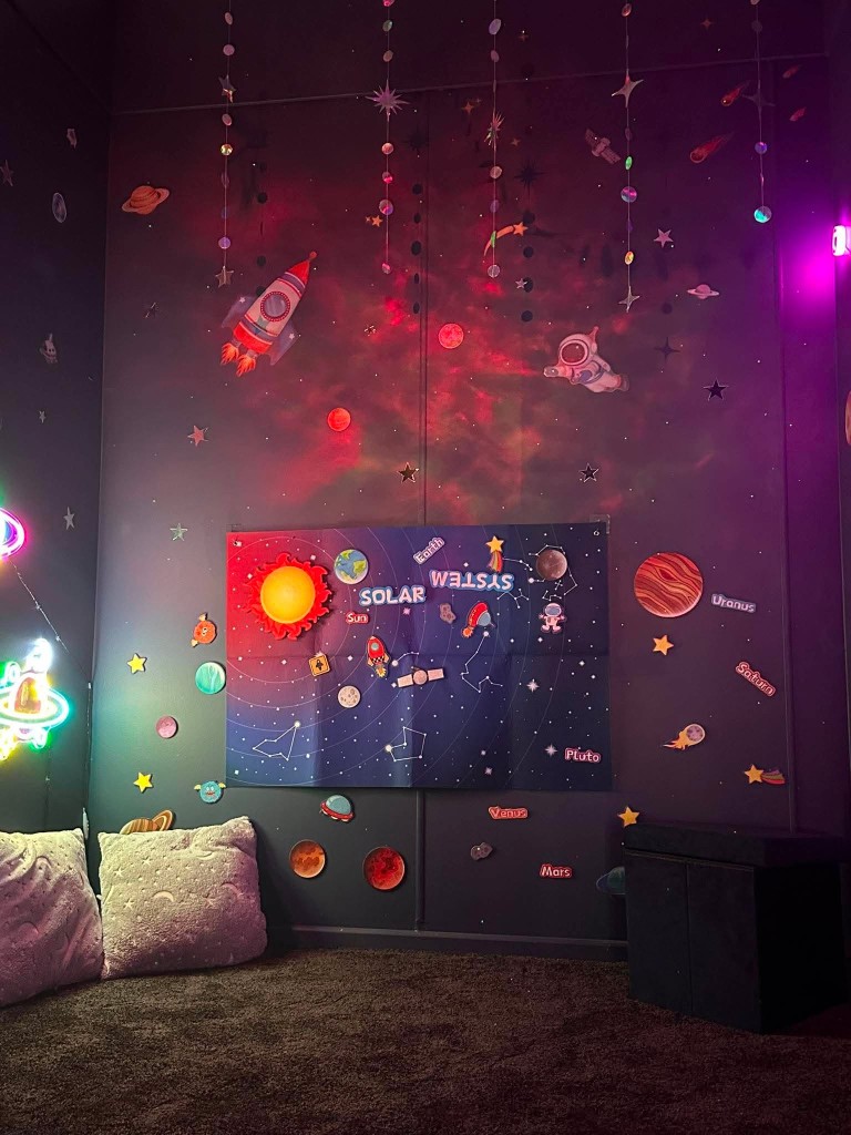The solar system wall in the space sensory room, with hanging stars, planet lights and moon cushions.