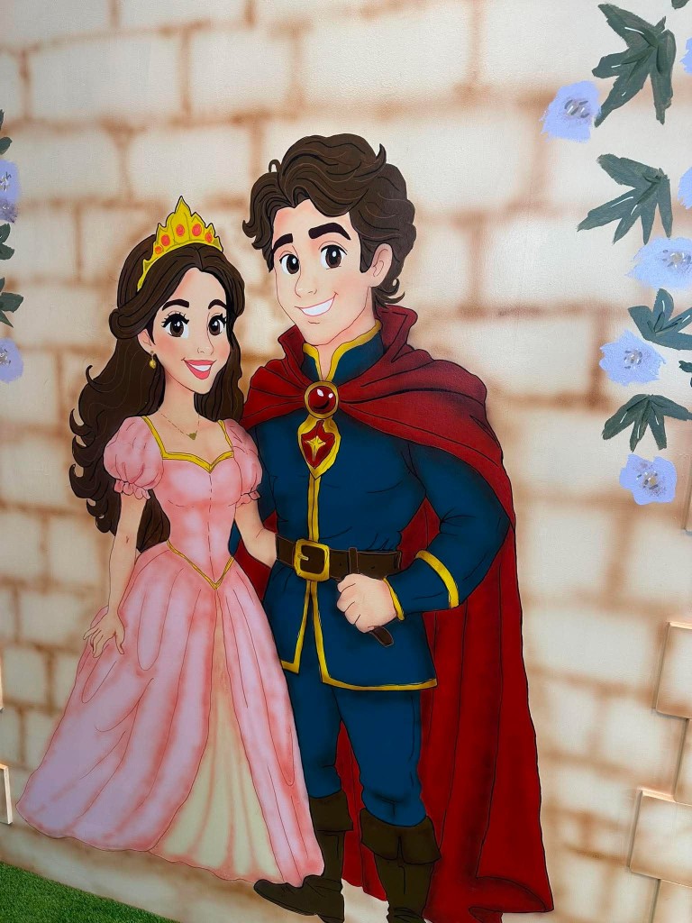 A painted prince and princess on the castle wall, with blue flowers climbing the stone.