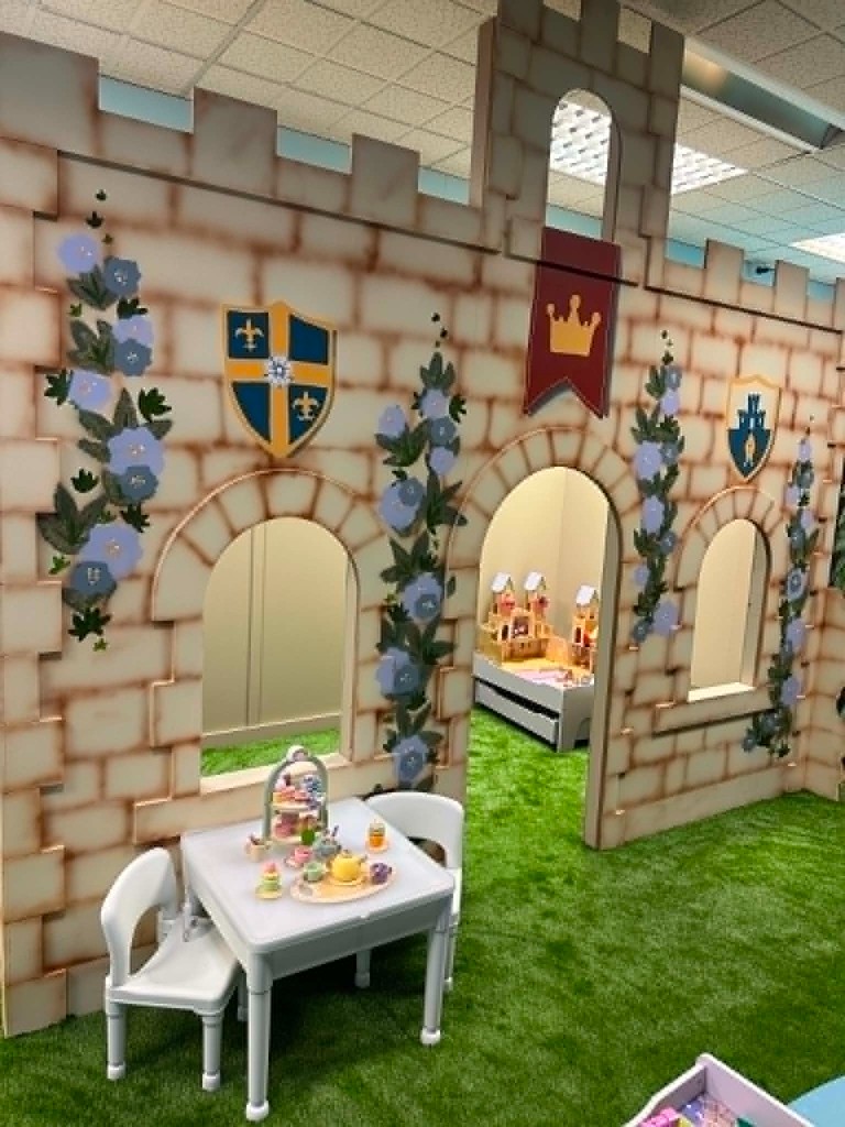The castle wall with a tea party table set on the grass in front of the arched doorway.
