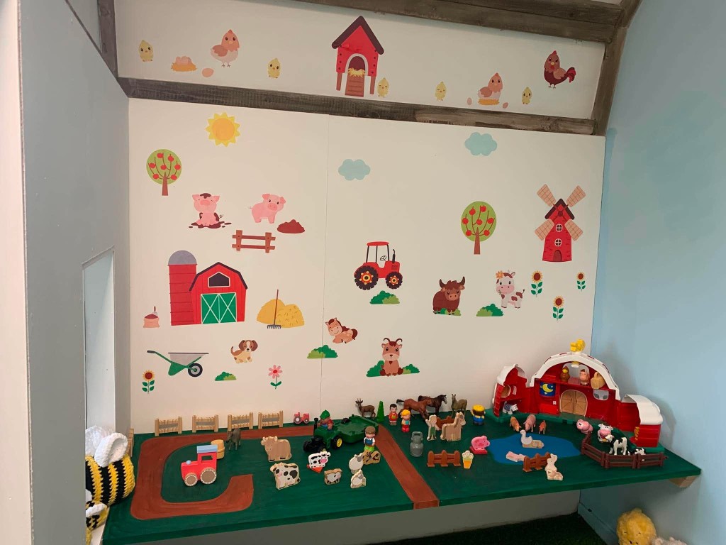 The farm play table, with barns, tractors and animals, and a farm mural on the wall.